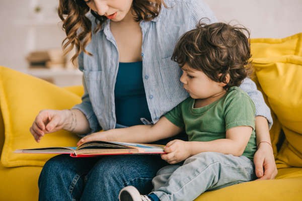 Frau und Kind sitzen auf einem Sofa und schauen in ein Buch