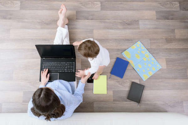 Mutter mit Kínd an der Hand schaut auf Laptop